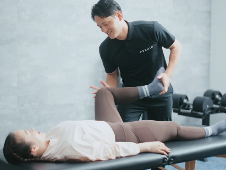 ストレッチベッドでお客様の脚を伸ばすトレーナー